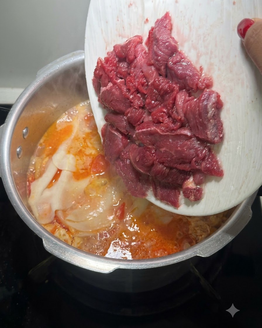 白いお皿から新鮮な生の赤い牛肉のスライスを、煮立っているスープの鍋に入れているところ。