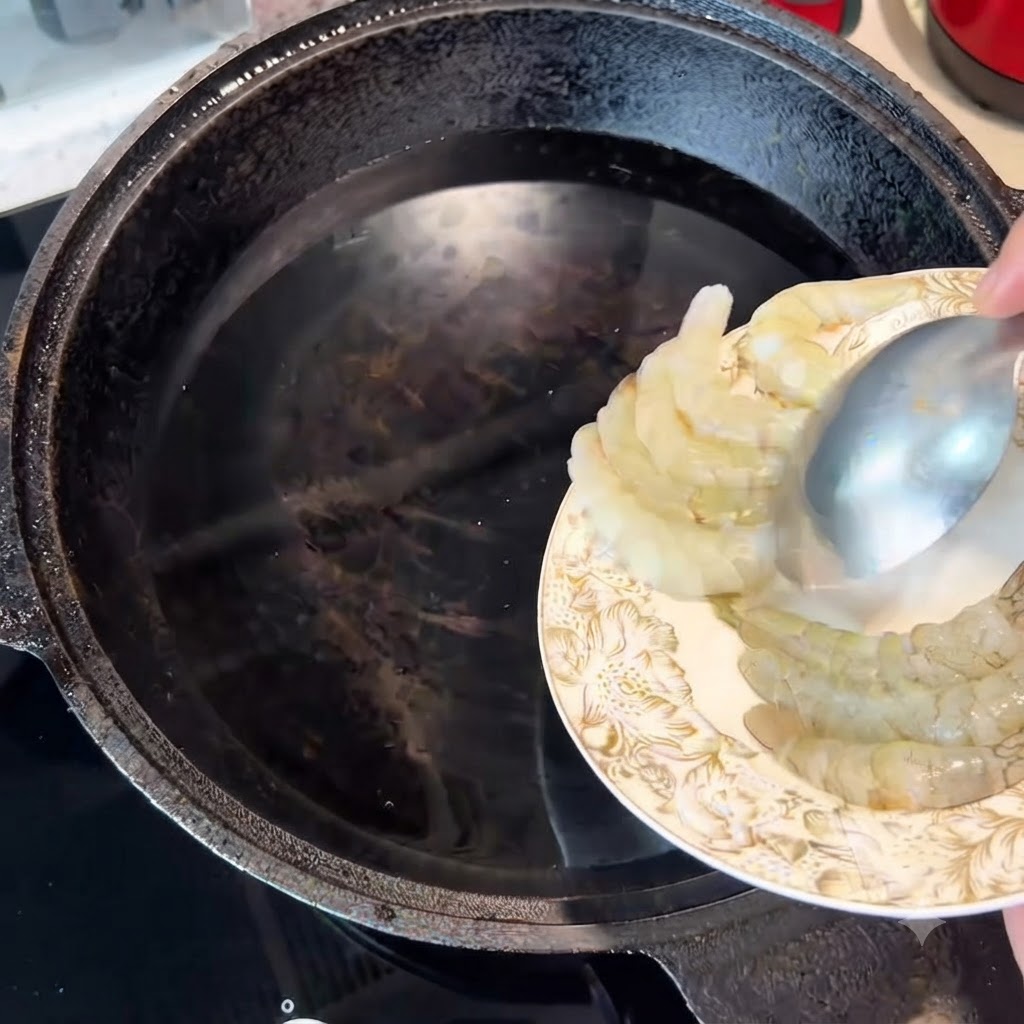 スプーンを使って生海老を水の入った鍋に入れている様子。