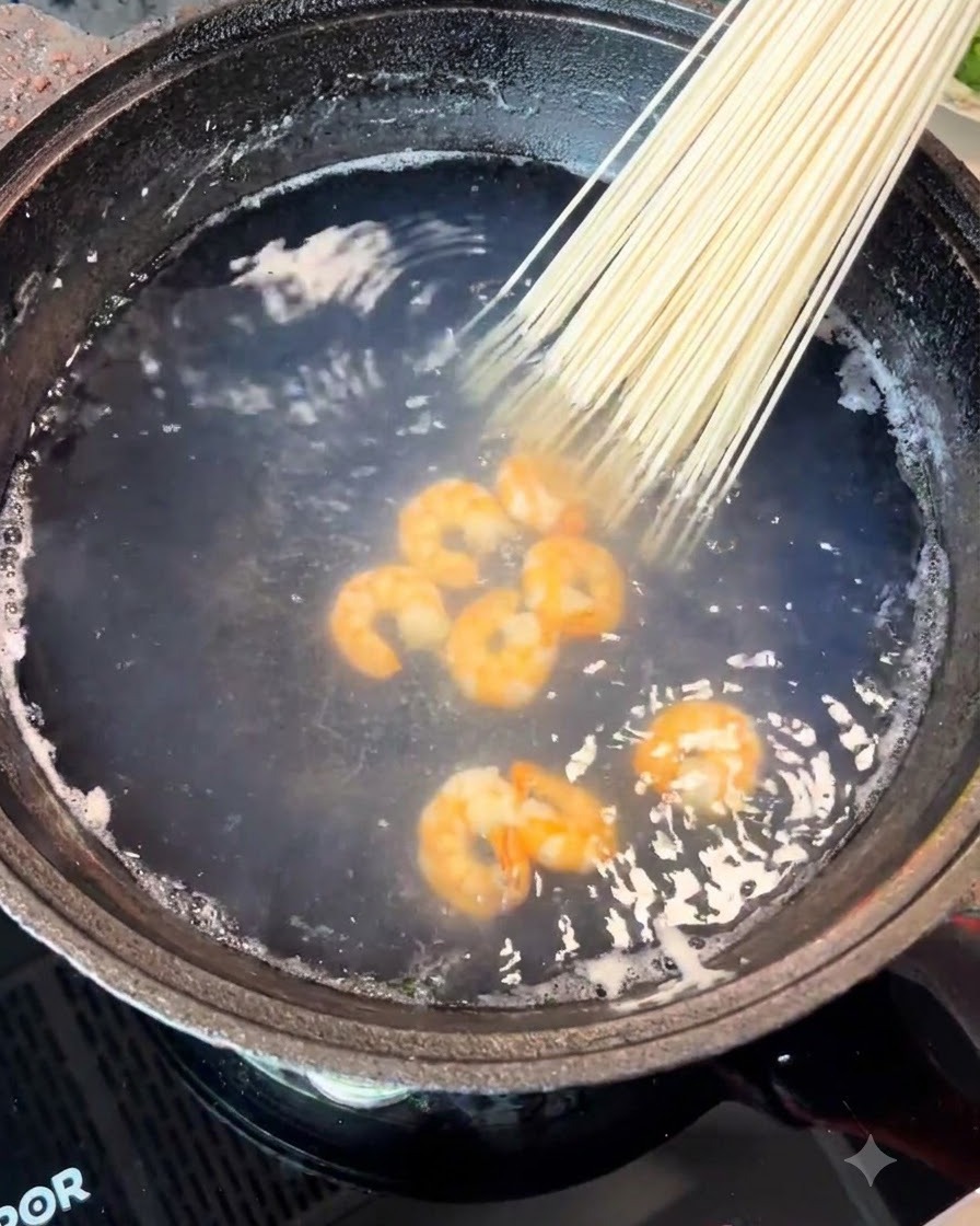 海老の入った鍋に乾燥麺の束を入れている様子。