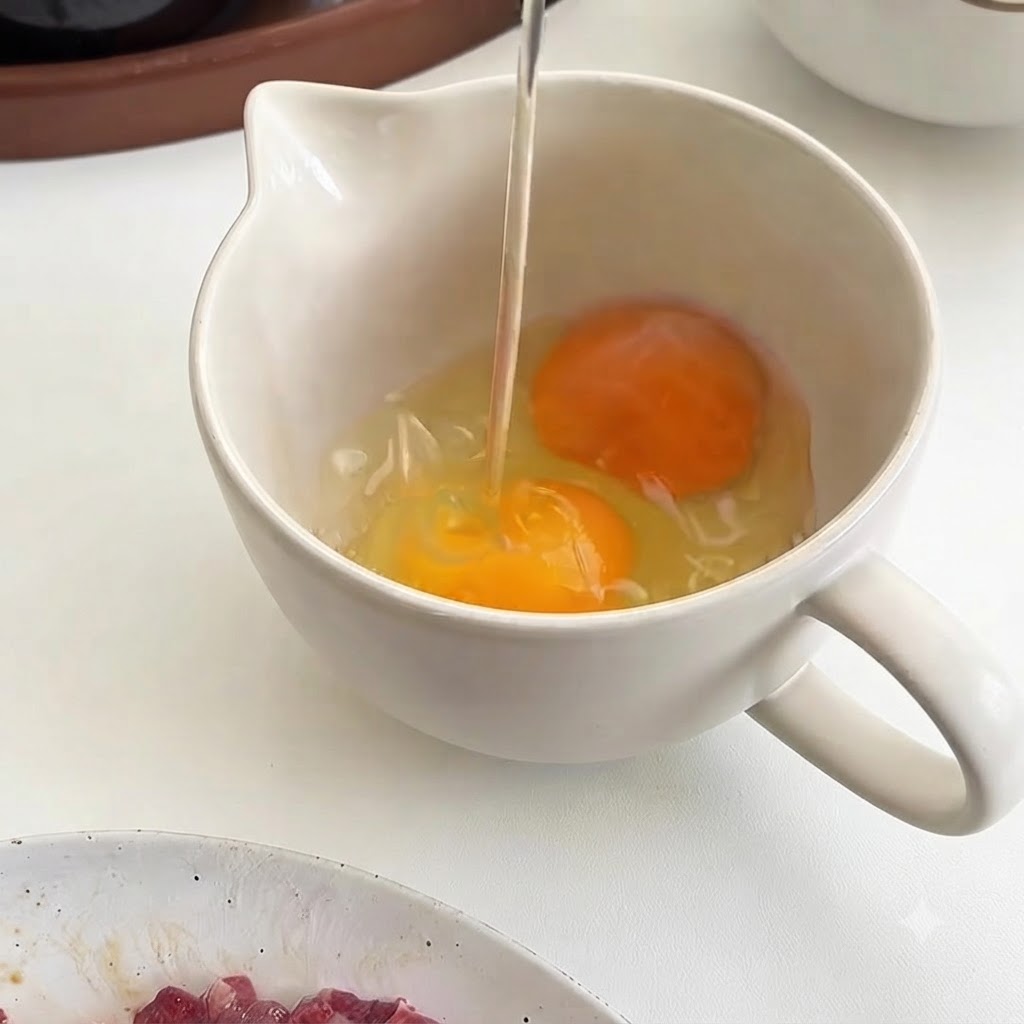 白いピッチャーに割り入れられた、鮮やかな黄身の3つの新鮮な生卵。