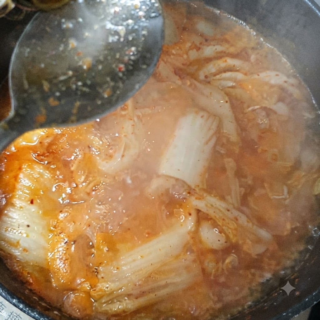 沸騰中のキムチチゲに醤油と粉唐辛子を混ぜ入れている様子。