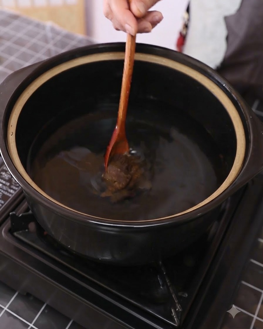 大酱正在深色锅中用木勺在水里搅拌。