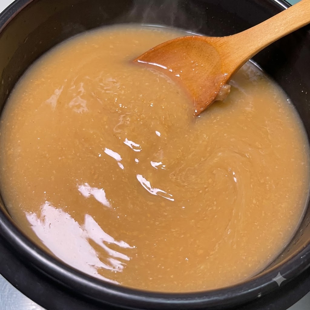 木製のスプーンで、煮立っているスープの中で味噌が完全に溶けるまで混ぜている様子。