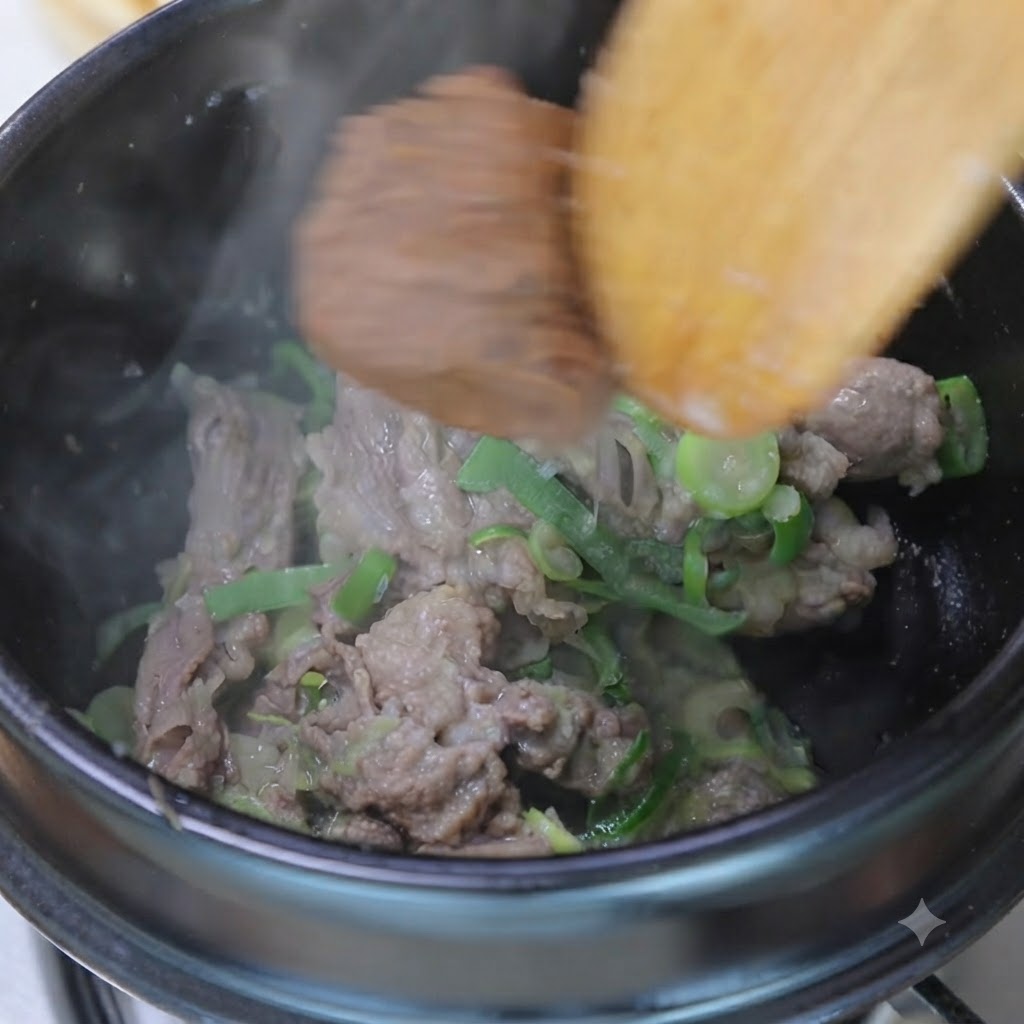 木製のスパチュラを使い、鍋の中でソテーした牛肉と香味野菜に味噌とコチュジャンを混ぜ合わせている様子。