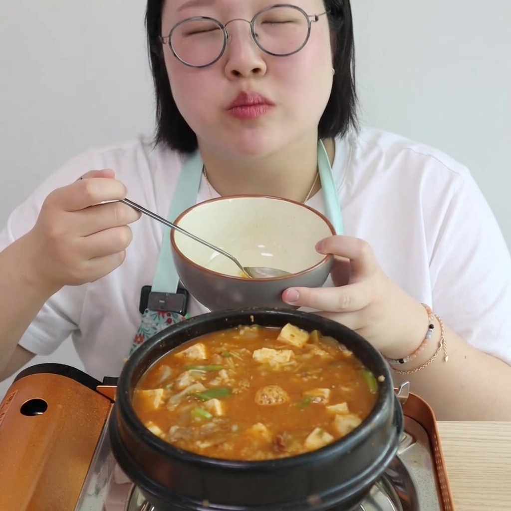 サービングボウルを持ちながら、味付けして炒めた牛肉とペーストが入った鍋に水を注いでいる様子。