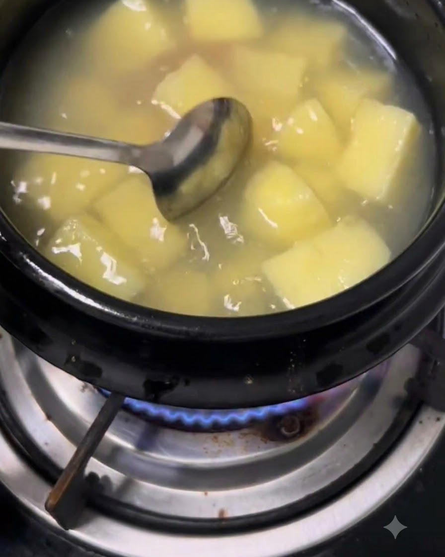 水とじゃがいもの入った鍋に、スプーンで味噌とチリペーストを溶かし入れる様子。