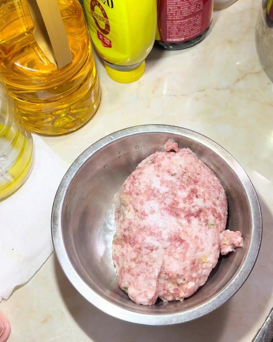 ボウルに入った豚ひき肉と、周囲に置かれた調味料や油