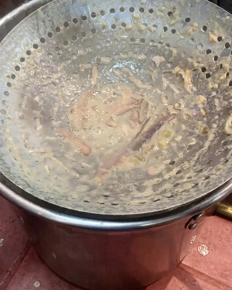 煮込んだ豚皮が入った鍋の中に、ハンドブレンダーが沈められているところ。
