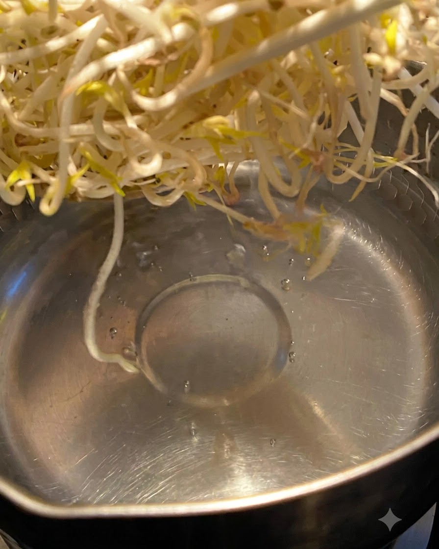 金属製の鍋の中の沸騰したお湯に浸され、茹でられているもやし。