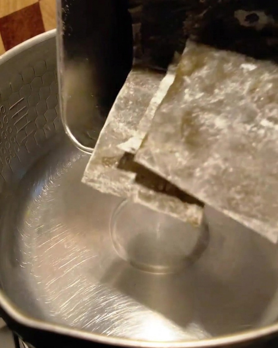 水が入った金属製の鍋に入れられる乾燥昆布の欠片。